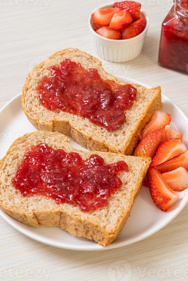 hausgemachtes Vollkornbrot mit Erdbeermarmelade und frischen Erdbeeren foto