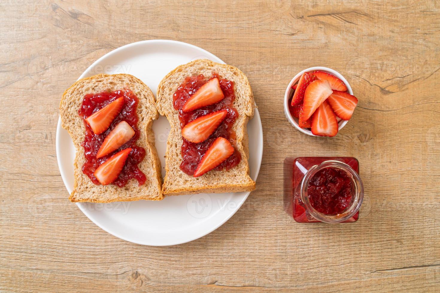 hausgemachtes Vollkornbrot mit Erdbeermarmelade und frischen Erdbeeren foto