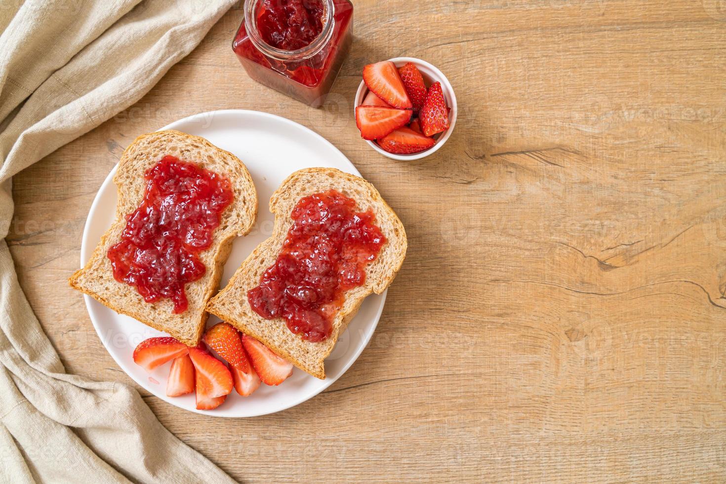 hausgemachtes Vollkornbrot mit Erdbeermarmelade und frischen Erdbeeren foto