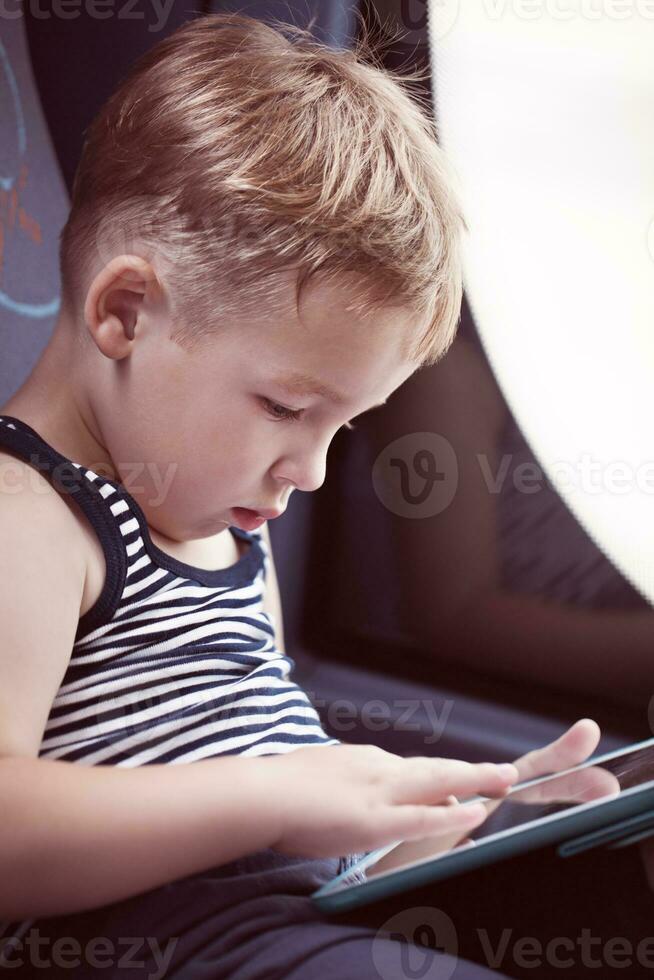wenig Kind mit berühren Pad während Reisen durch Bus foto