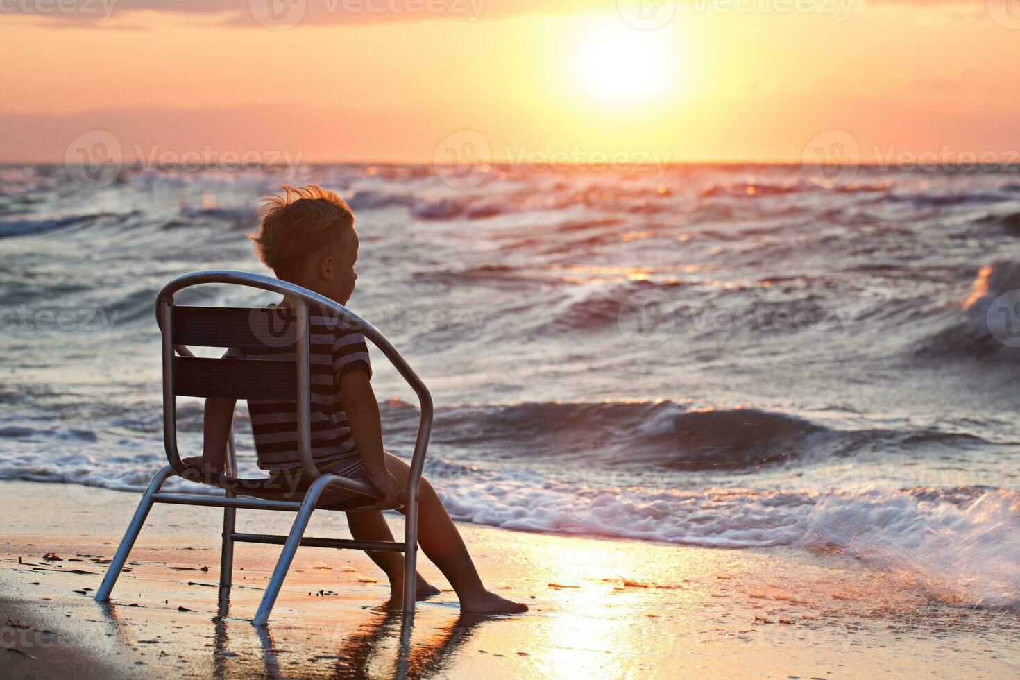 wenig Kind suchen beim Sonnenuntergang Sitzung durch das Meer foto