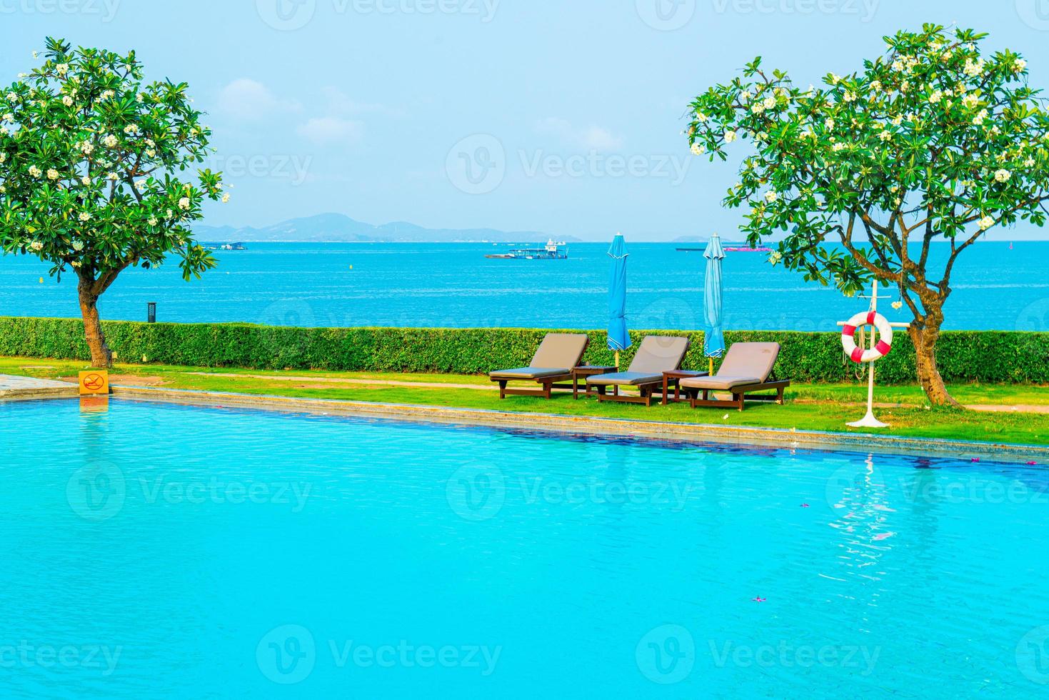 Stuhlpool rund um den Pool mit Meereshintergrund - Ferien- und Urlaubskonzept foto