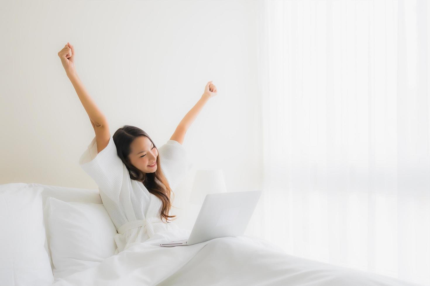 Porträt schöne junge asiatische Frauen mit Kaffeetasse und Computer-Laptop auf dem Bett foto