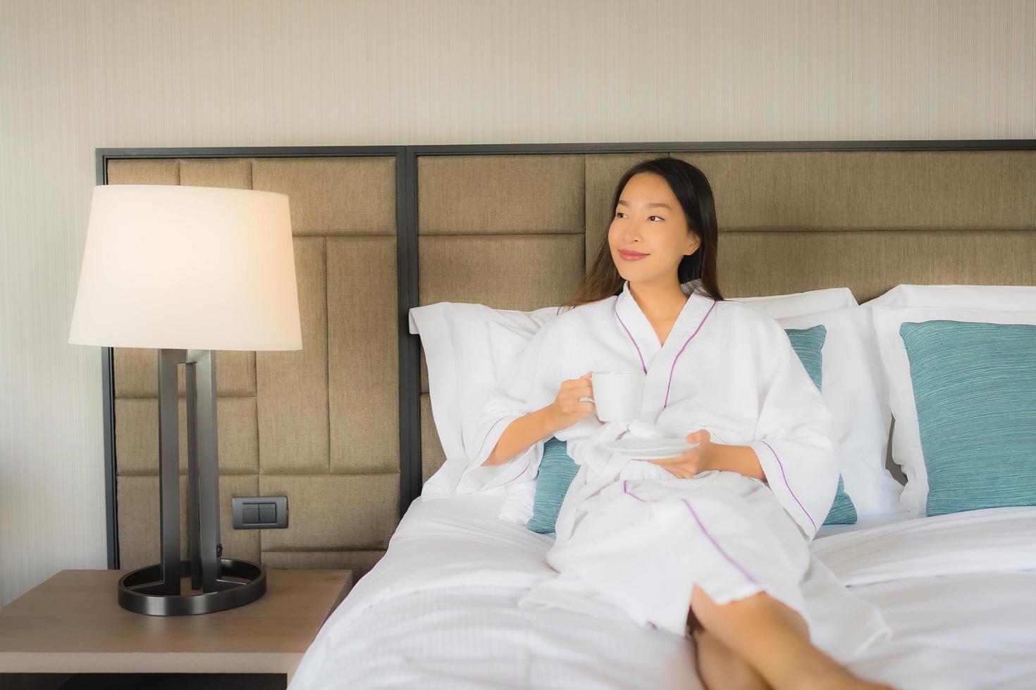 Porträt schöne junge asiatische Frauen mit Kaffeetasse auf dem Bett foto