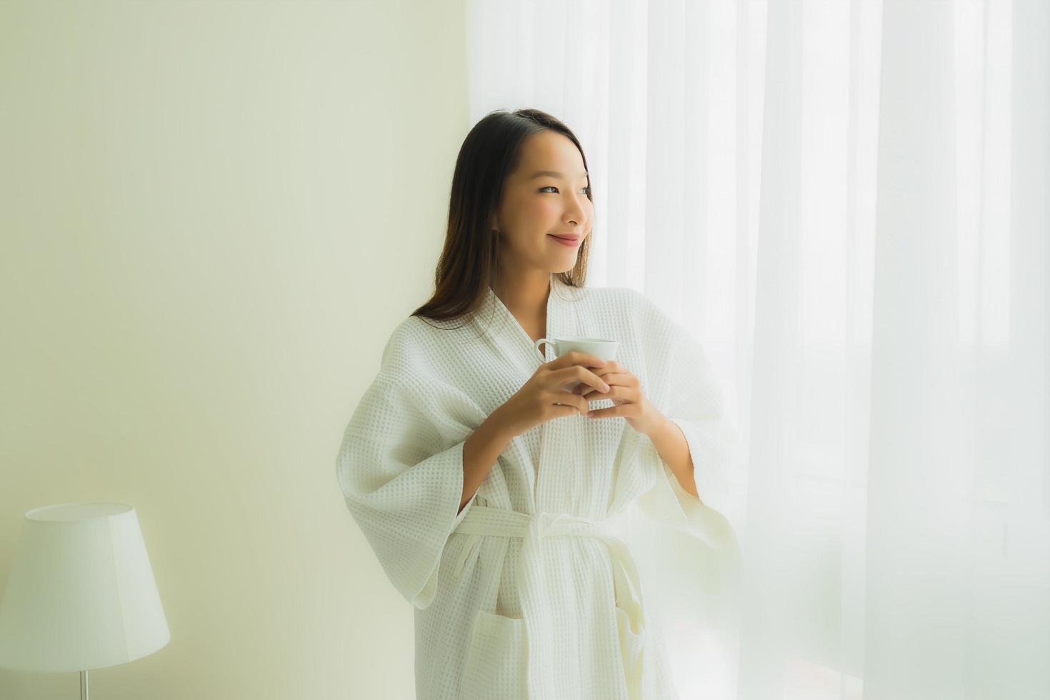 Porträt schöne junge asiatische Frauen mit Kaffeetasse im Schlafzimmer foto