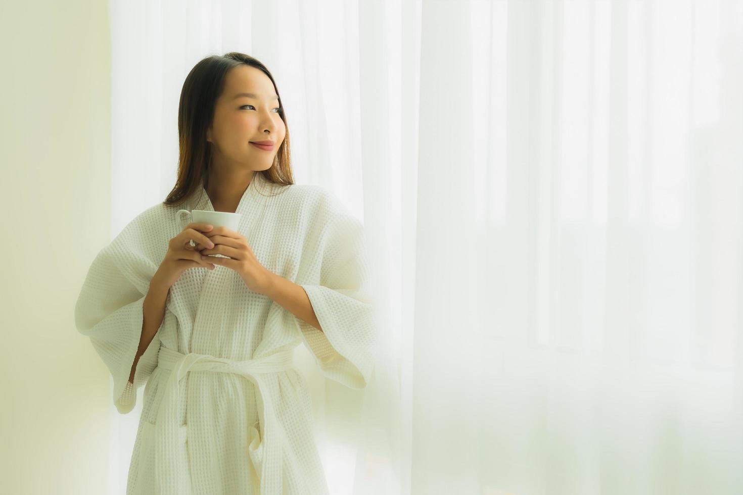 Porträt schöne junge asiatische Frauen mit Kaffeetasse im Schlafzimmer foto