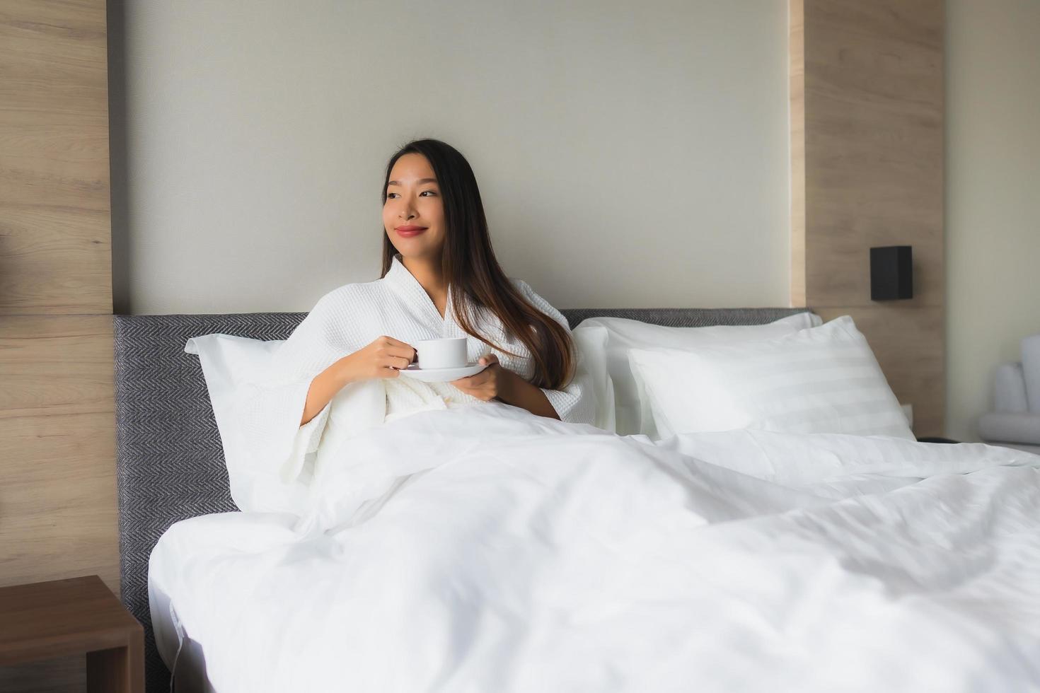 Porträt schöne junge asiatische Frauen mit Kaffeetasse auf dem Bett foto