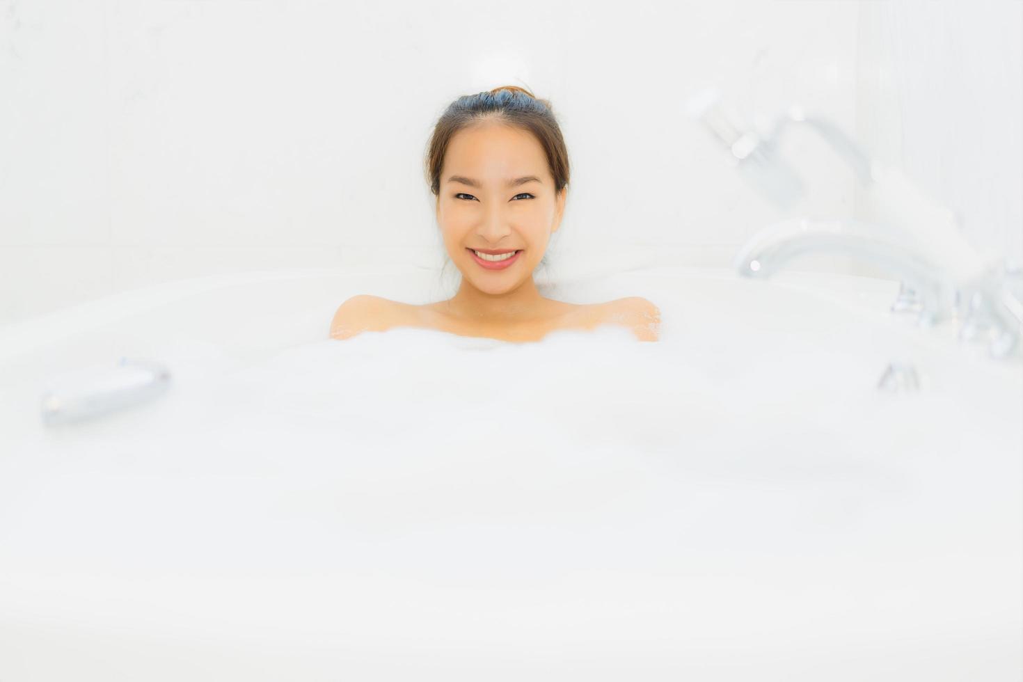 Porträt schöne junge asiatische Frau nimmt eine Badewanne im Badezimmer foto