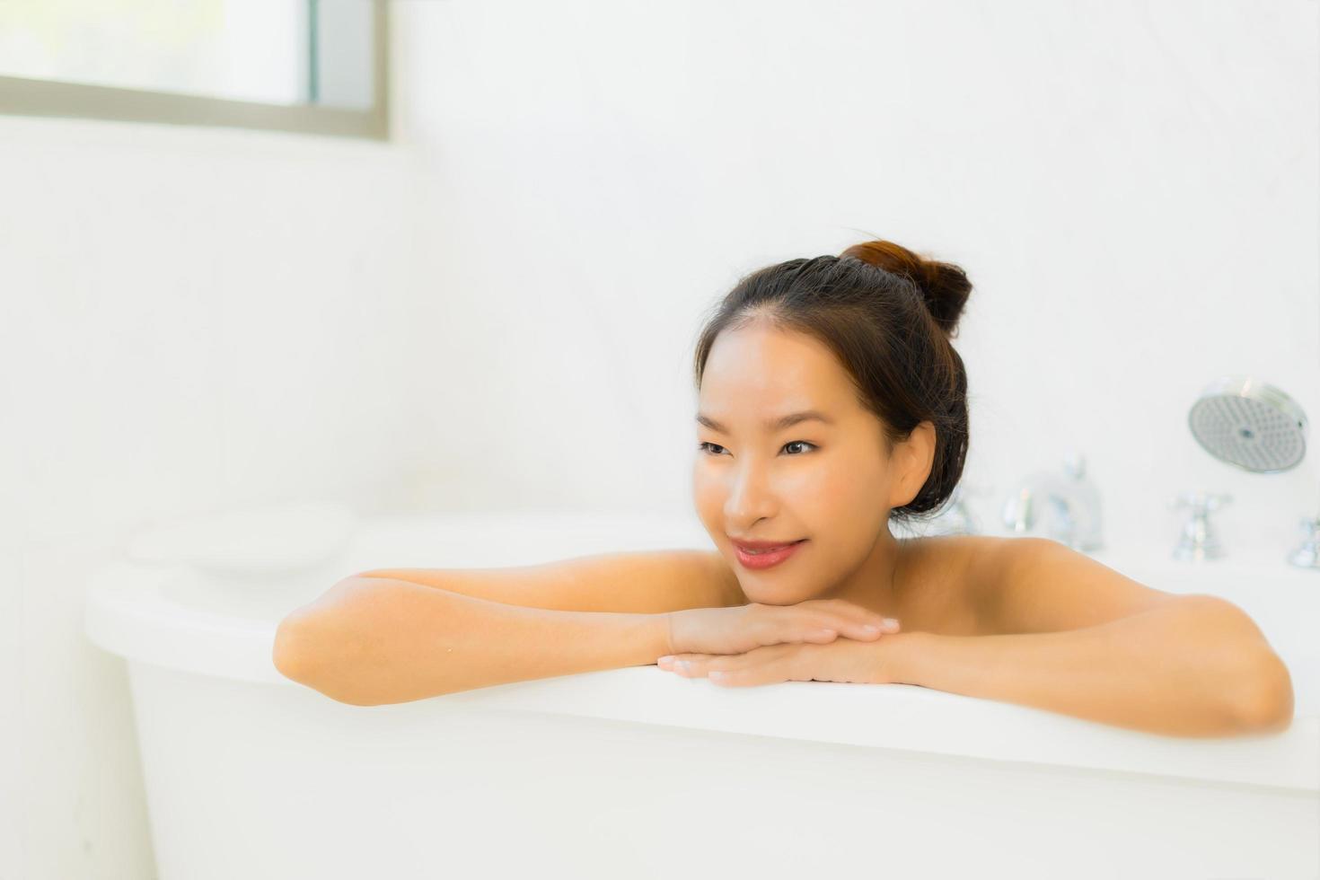 Porträt schöne junge asiatische Frau nimmt eine Badewanne im Badezimmer foto