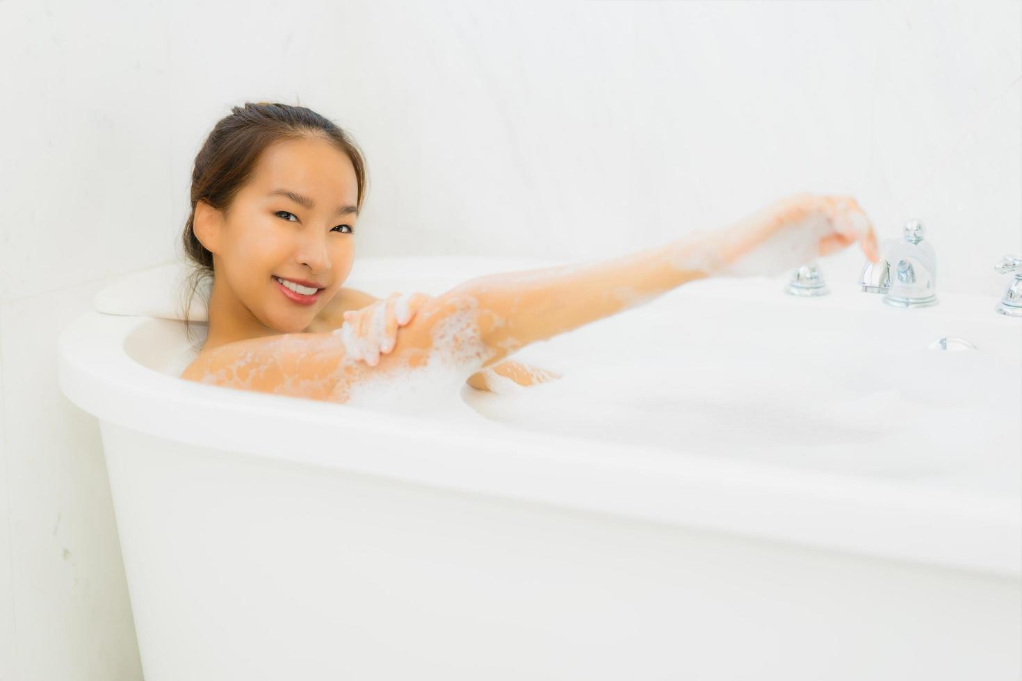 Porträt schöne junge asiatische Frau nimmt eine Badewanne im Badezimmer foto