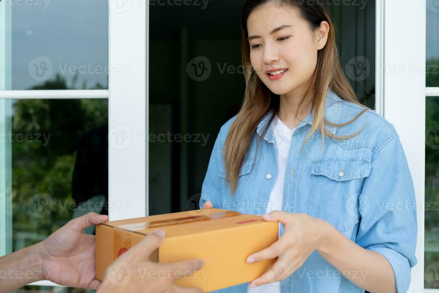 glücklich lächelnd Frau erhält Kisten Paket von Kurier im Vorderseite Haus. Lieferung Mann senden liefern äußern. online Einkaufen, Papier Behälter, wegbringen, Briefträger, Lieferung Service, Pakete foto