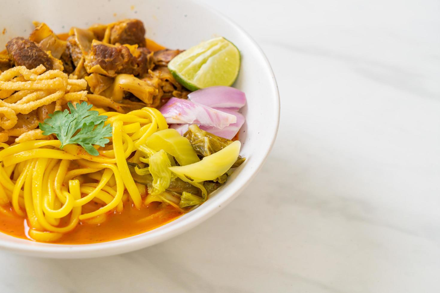 Nordthailändische Nudel-Curry-Suppe mit geschmortem Schweinefleisch foto