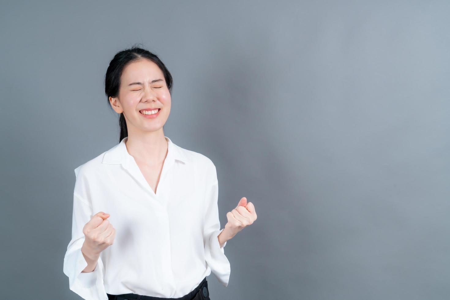 asiatische frau, die sich über ihren erfolg und sieg freut, ballt ihre fäuste vor freude glückliche frau, die glücklich ist, ihr ziel und ihre ziele zu erreichen positive emotionen gefühle foto