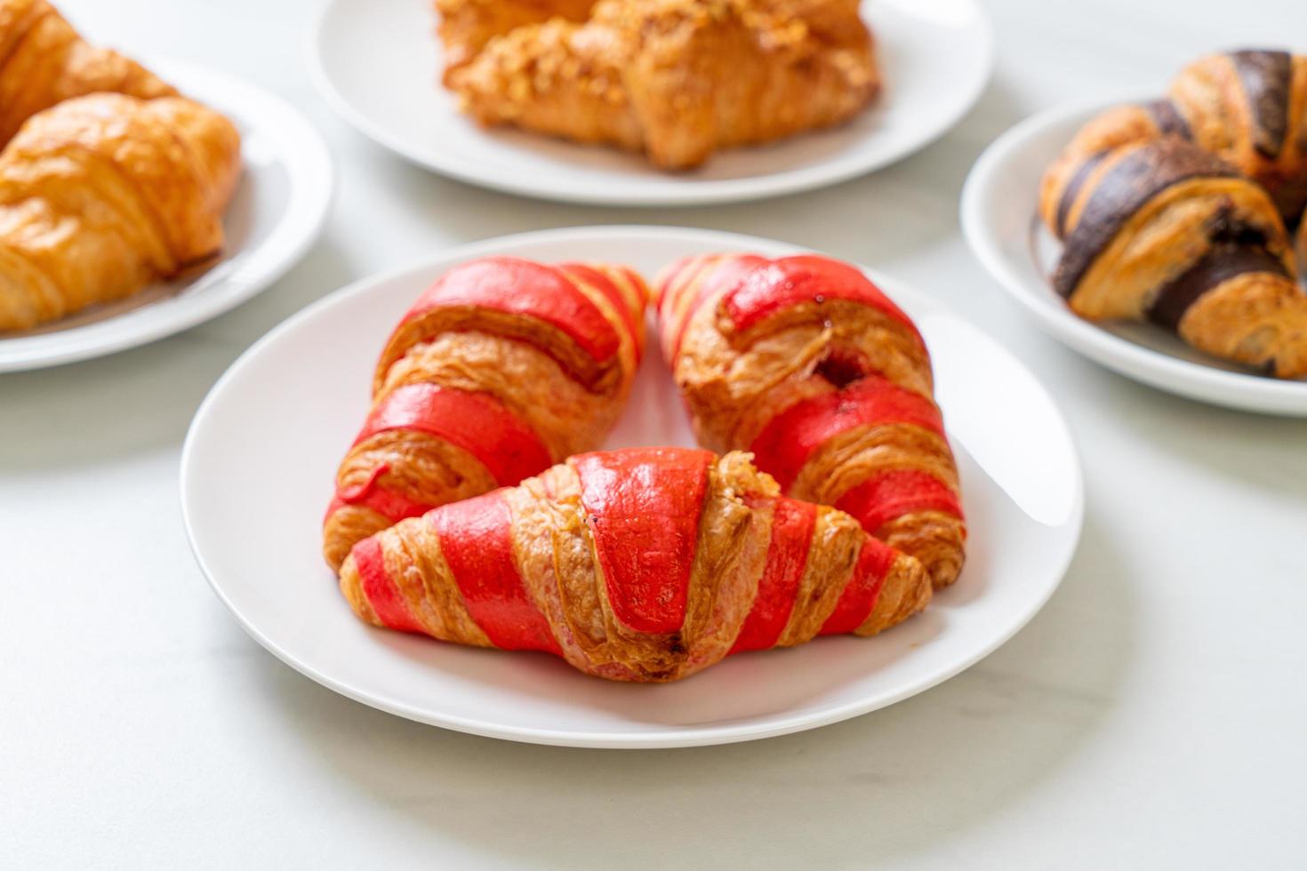 frisches Croissant mit Erdbeermarmeladesauce auf Teller foto