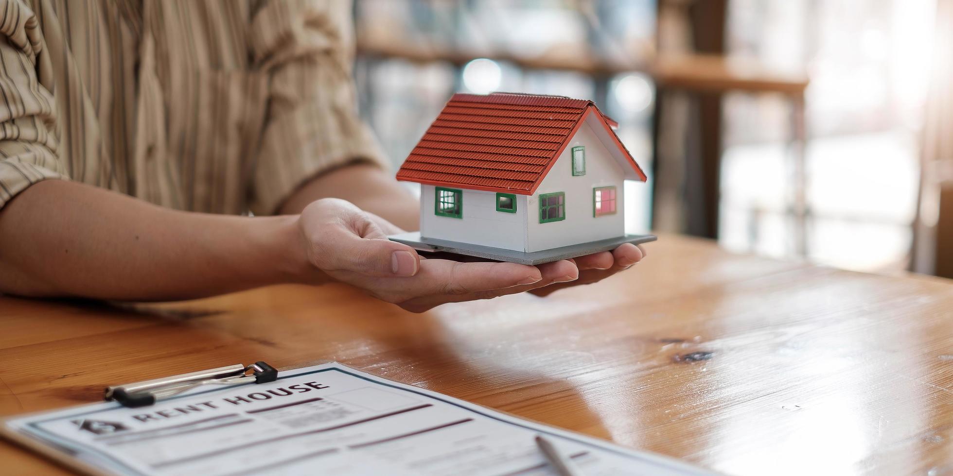 immobilienmakler mit hausmodell auf hans angebotshaus. Sachversicherung und Sicherheitskonzept foto