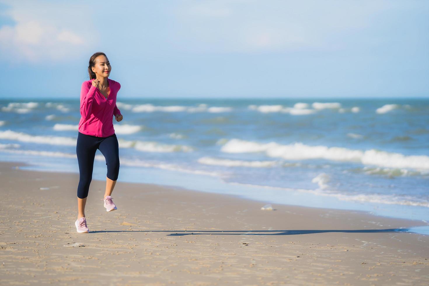 Porträt schöne junge asiatische Frau, die auf dem tropischen Naturstrand Meer Ozean läuft und trainiert foto