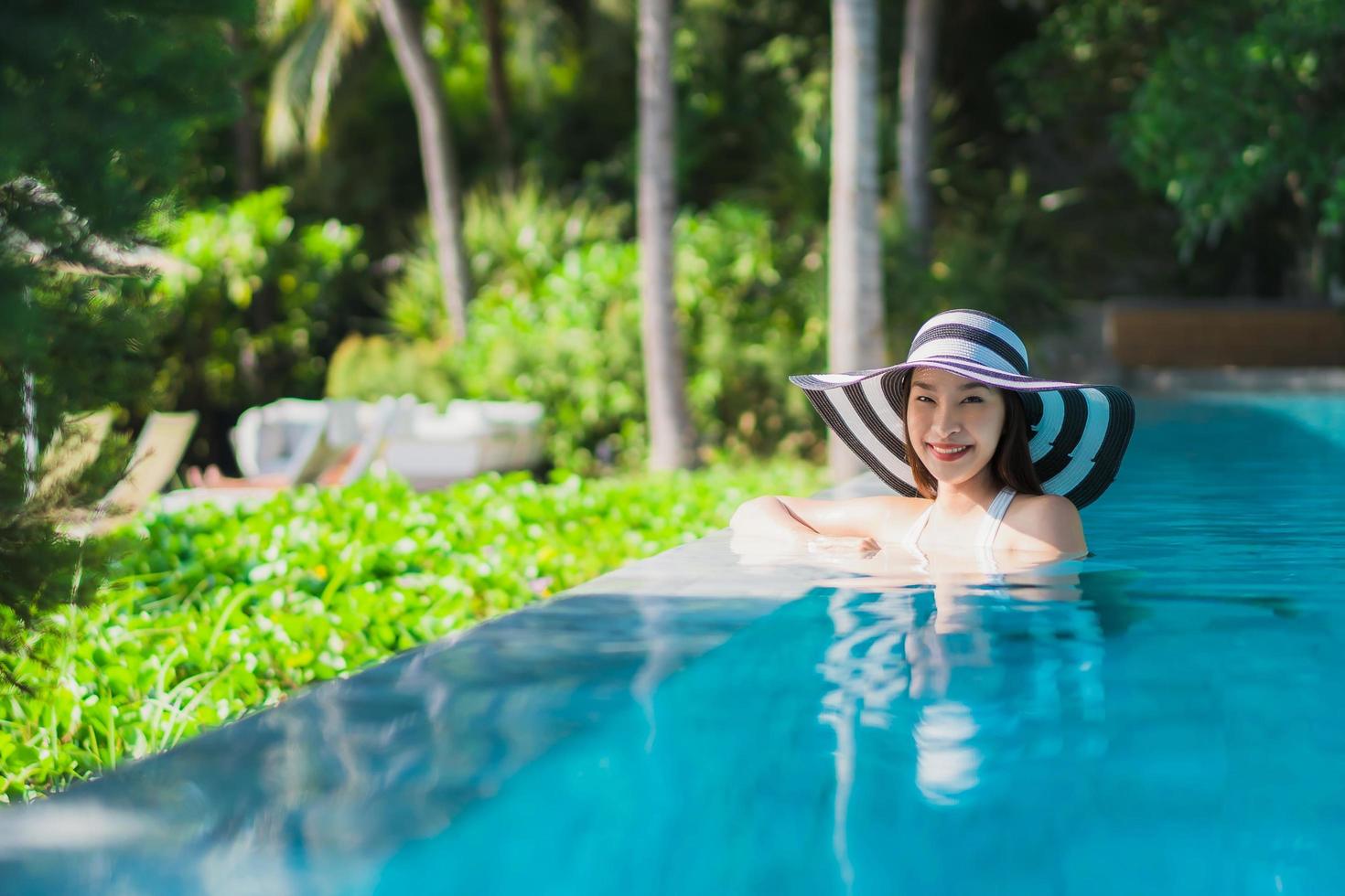 Porträt schöne junge asiatische Frau glückliches Lächeln im Schwimmbad um Resort und Hotel? foto