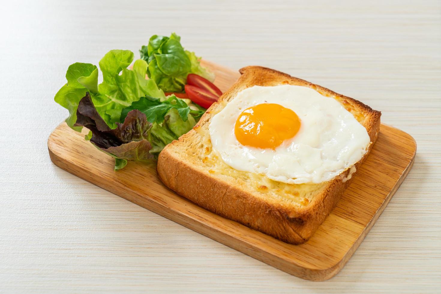 hausgemachtes Brot geröstet mit Käse und Spiegelei obenauf mit Gemüsesalat zum Frühstück foto