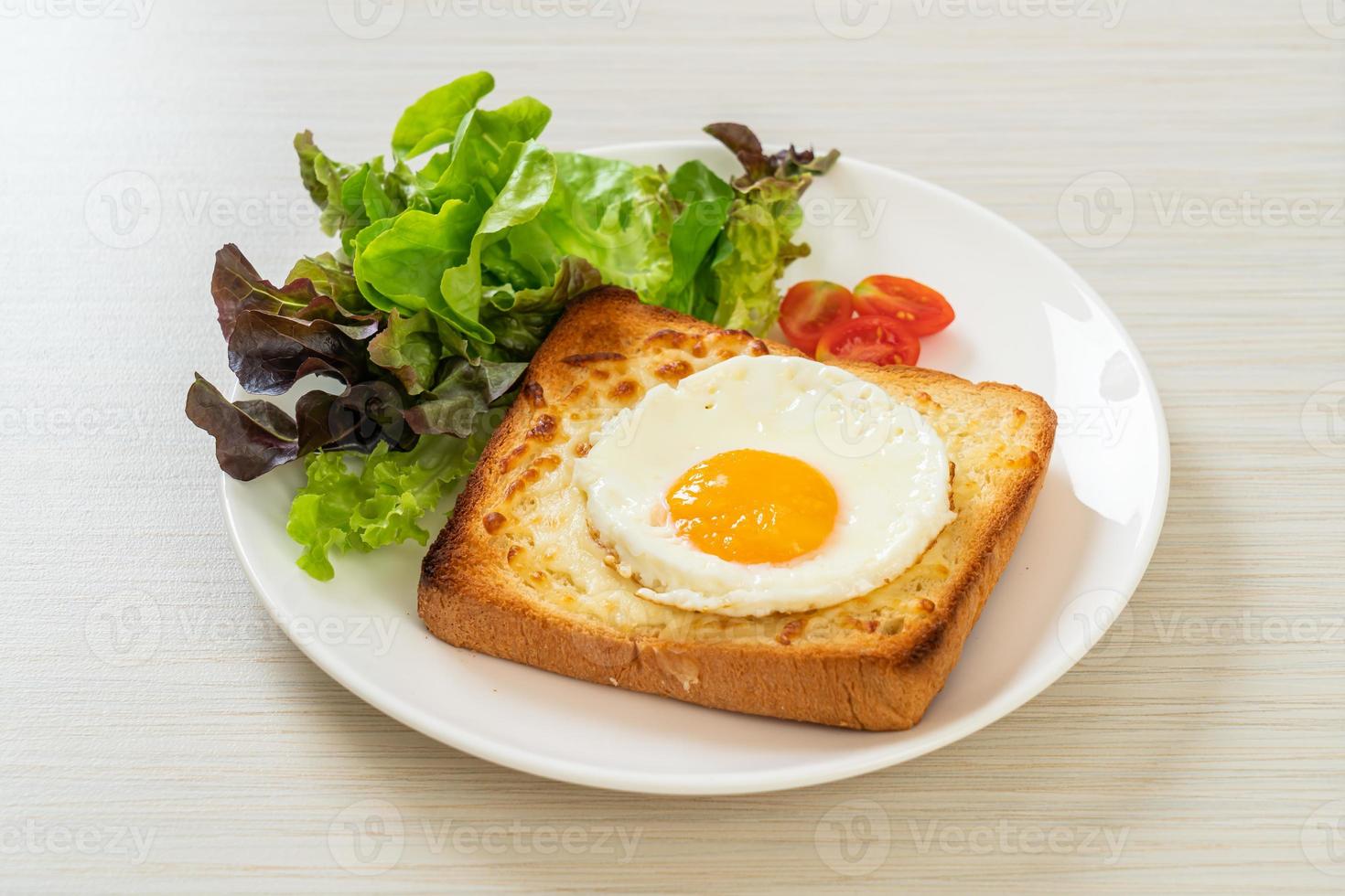 hausgemachtes Brot geröstet mit Käse und Spiegelei obenauf mit Gemüsesalat zum Frühstück foto