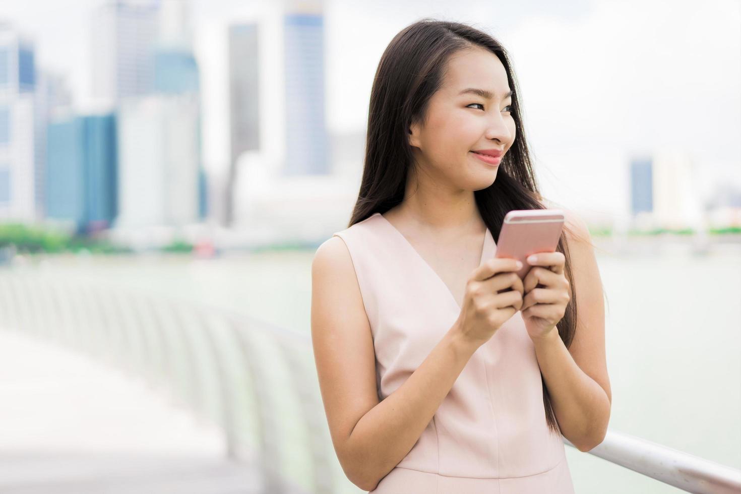 asiatische Frau, die Smartphone oder Handy zum Sprechen oder Text verwendet foto