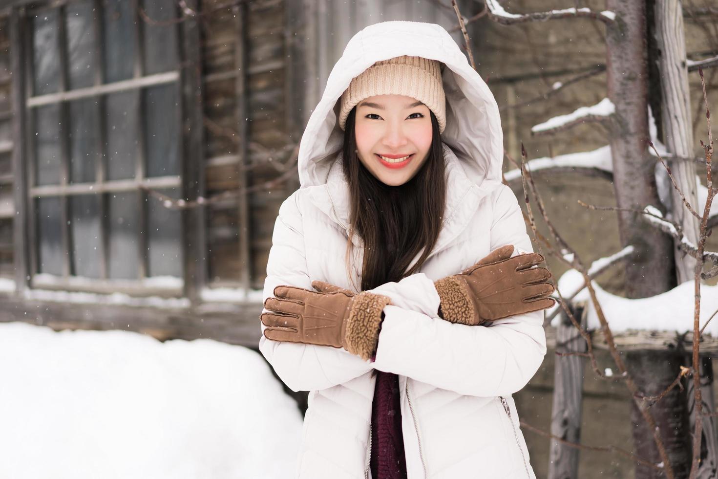 schöne junge asiatische frau, die glücklich für reisen in der schneewintersaison lächelt foto