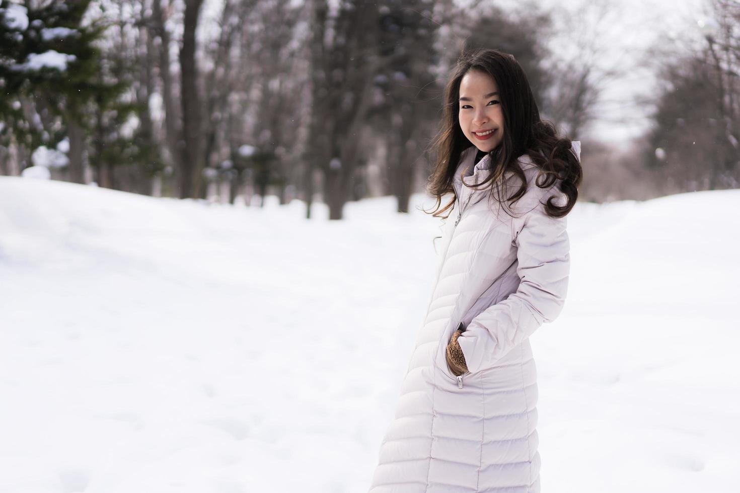 schöne junge asiatische frau, die glücklich für reisen in der schneewintersaison lächelt foto