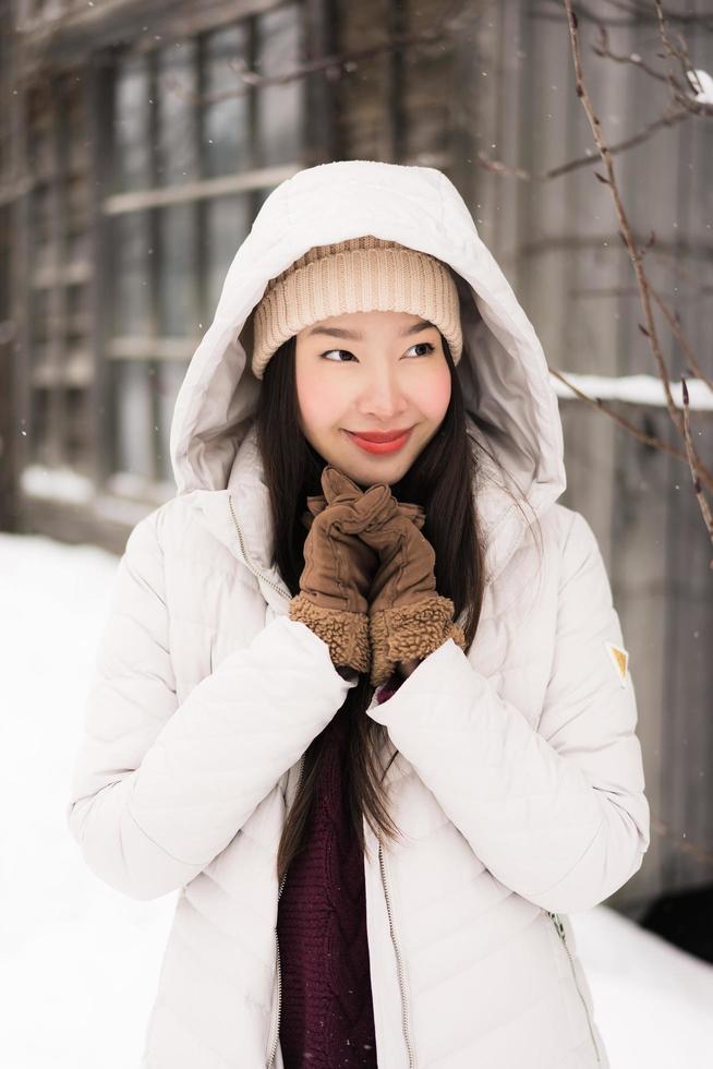 schöne junge asiatische frau, die glücklich für reisen in der schneewintersaison lächelt foto