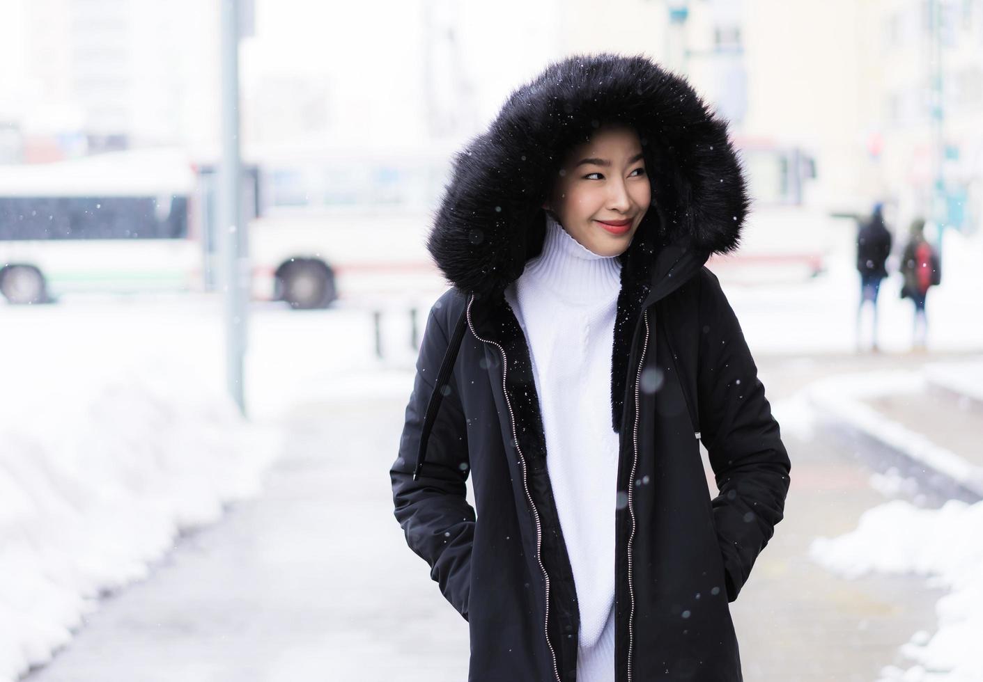 schöne junge asiatische frau, die glücklich für reisen in der schneewintersaison lächelt foto