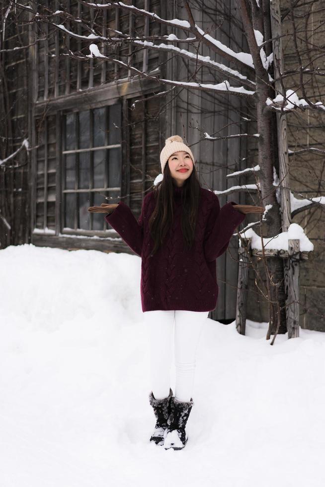 schöne junge asiatische frau, die glücklich für reisen in der schneewintersaison lächelt foto