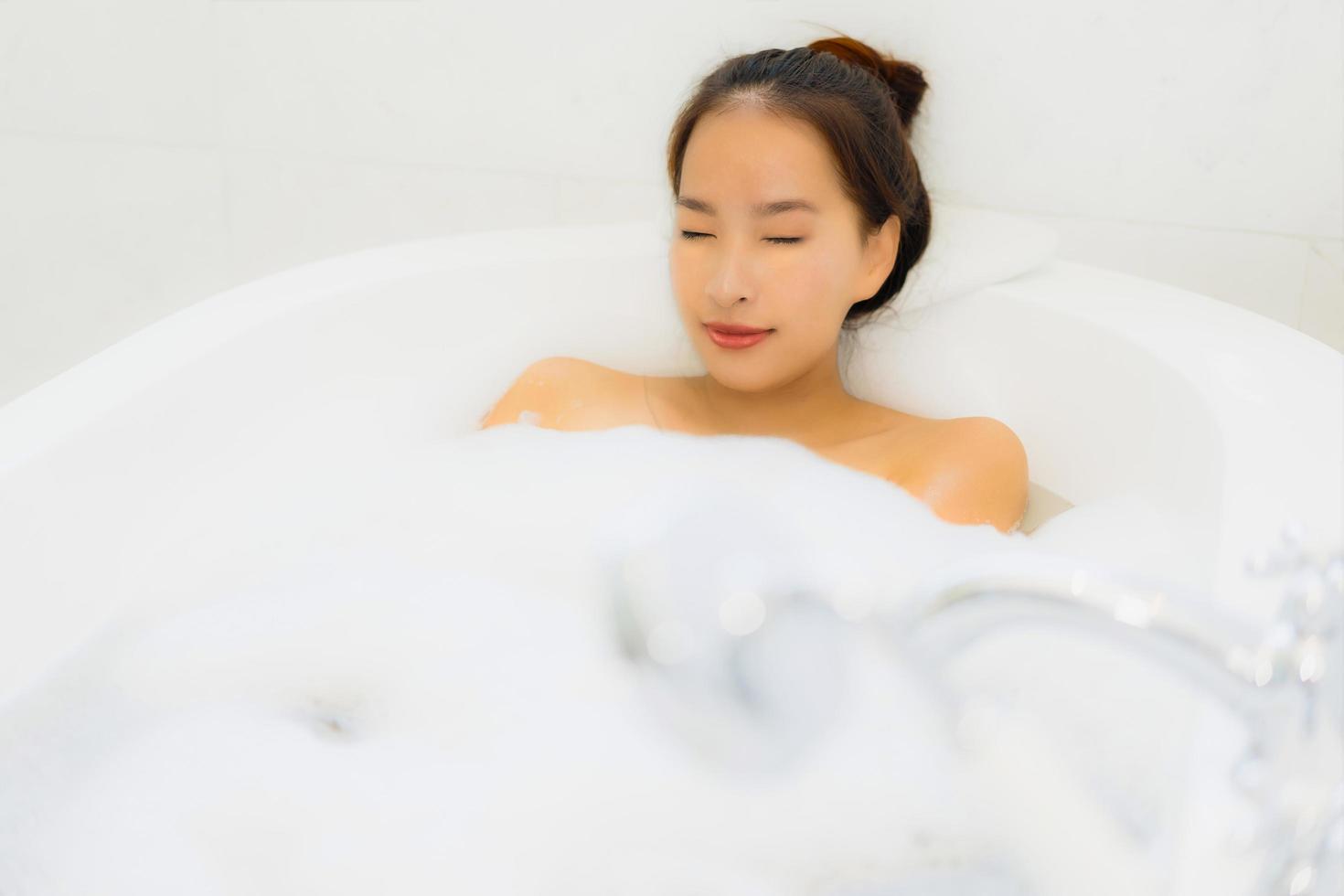 Porträt schöne junge asiatische Frau nimmt eine Badewanne im Badezimmer foto