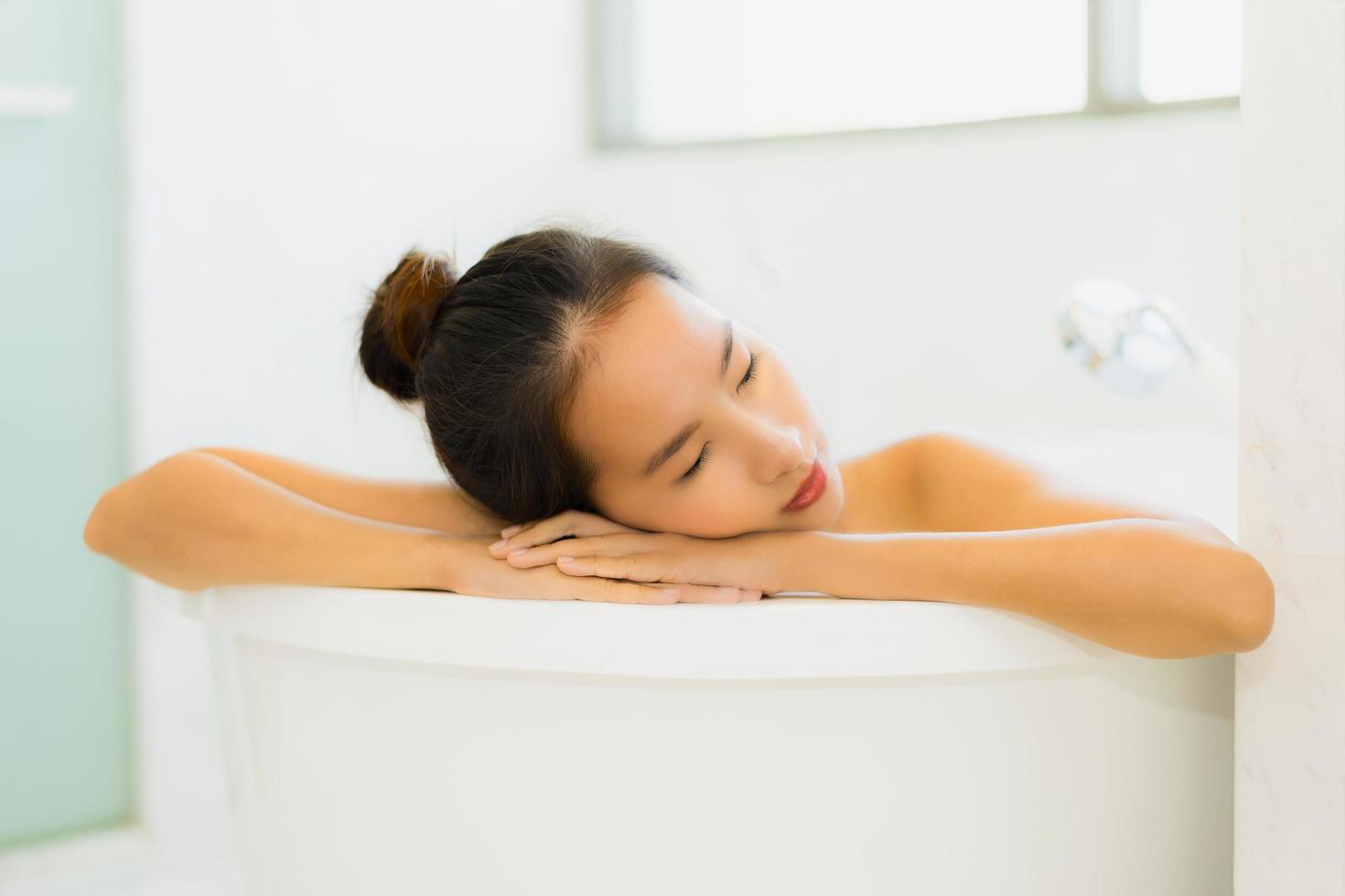 Porträt schöne junge asiatische Frau nimmt eine Badewanne im Badezimmer foto