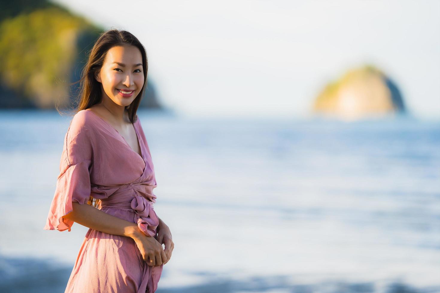 Porträt junge schöne asiatische Frau Spaziergang Lächeln und glücklich am Strand Meer und Ozean foto