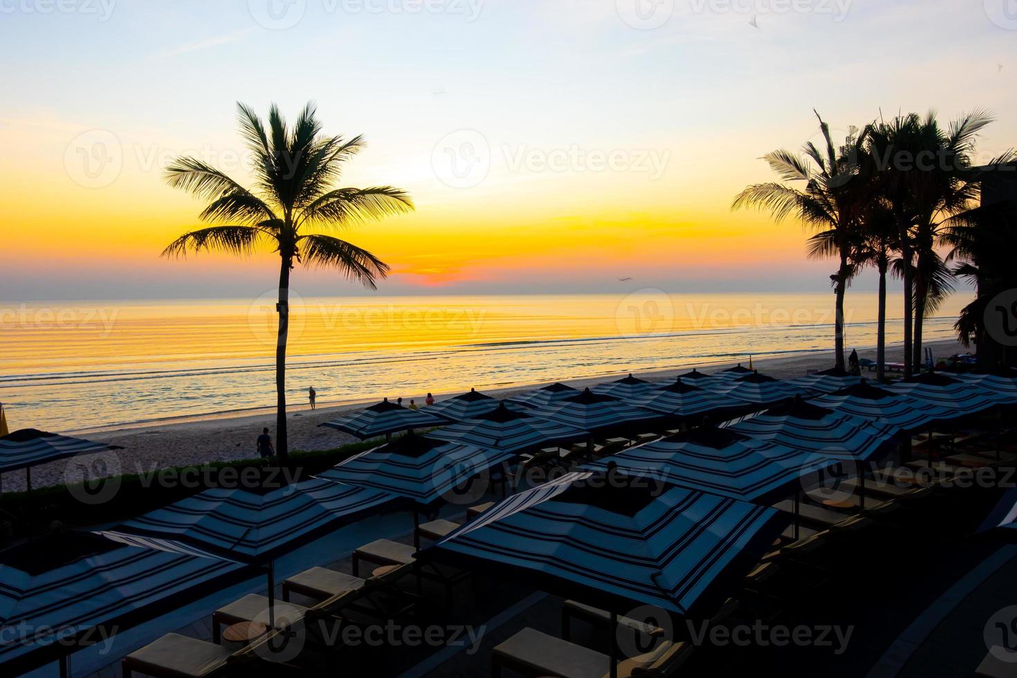 Sonnenschirme und Stühle rund um den Außenpool im Hotelresort für Urlaubsreisen im Hintergrund foto