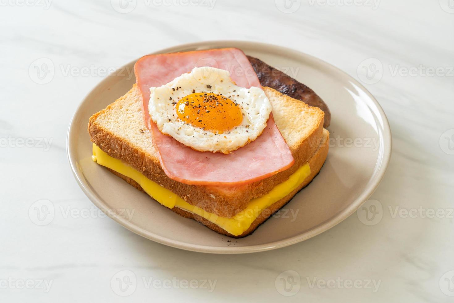 hausgemachtes Brot, gerösteter Käse, belegter Schinken und Spiegelei mit Schweinswurst zum Frühstück foto