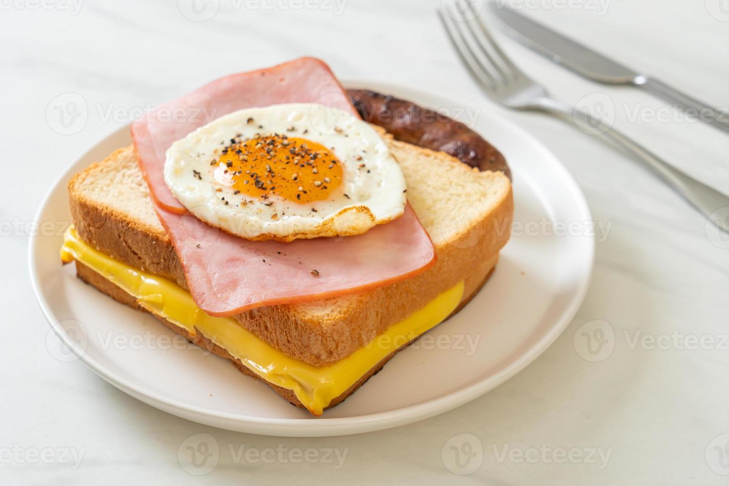 hausgemachtes Brot, gerösteter Käse, belegter Schinken und Spiegelei mit Schweinswurst zum Frühstück foto