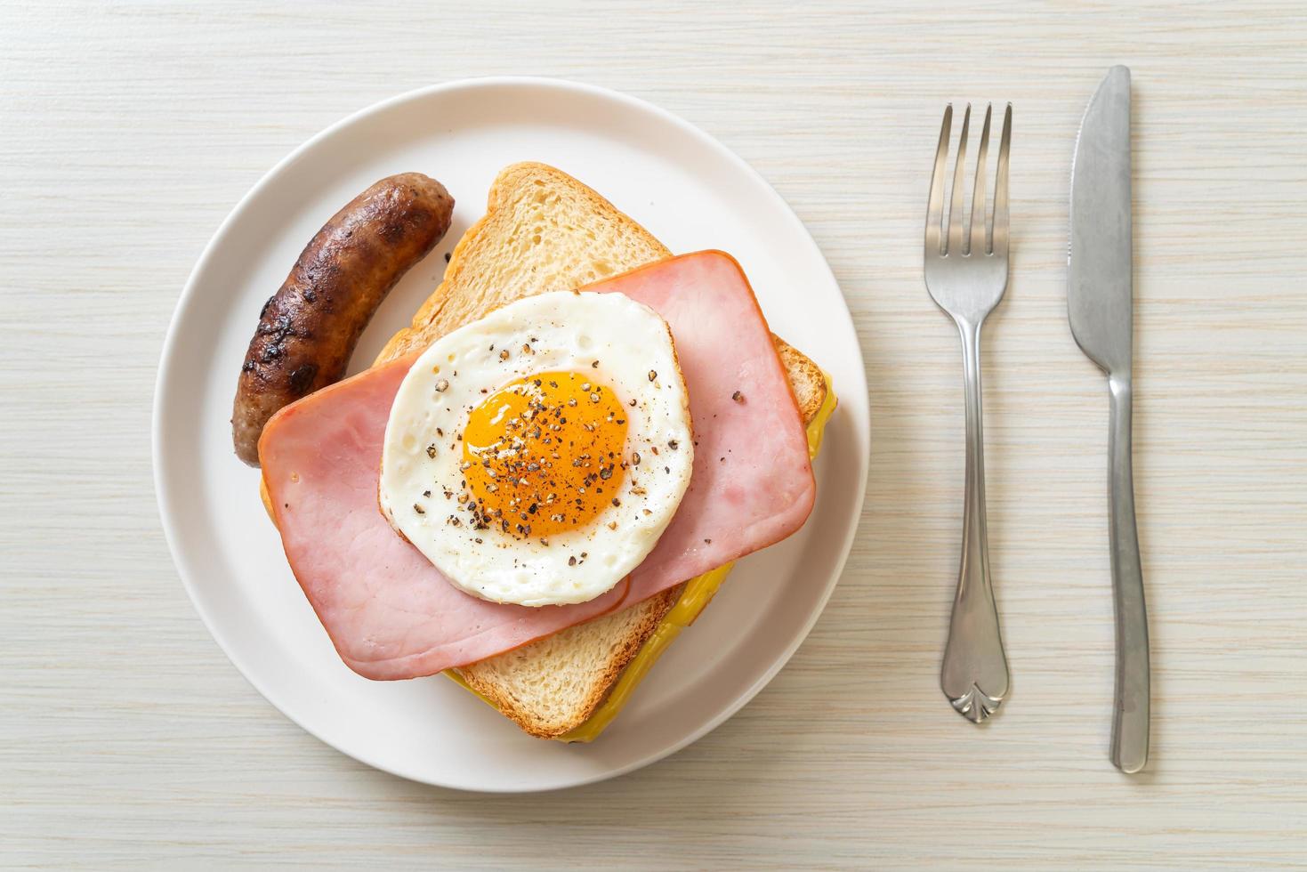 hausgemachtes Brot, gerösteter Käse, belegter Schinken und Spiegelei mit Schweinswurst zum Frühstück foto