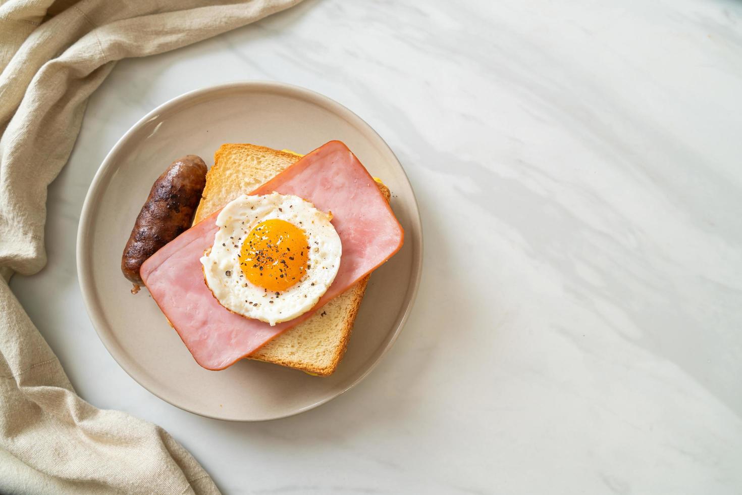 hausgemachtes Brot, gerösteter Käse, belegter Schinken und Spiegelei mit Schweinswurst zum Frühstück foto