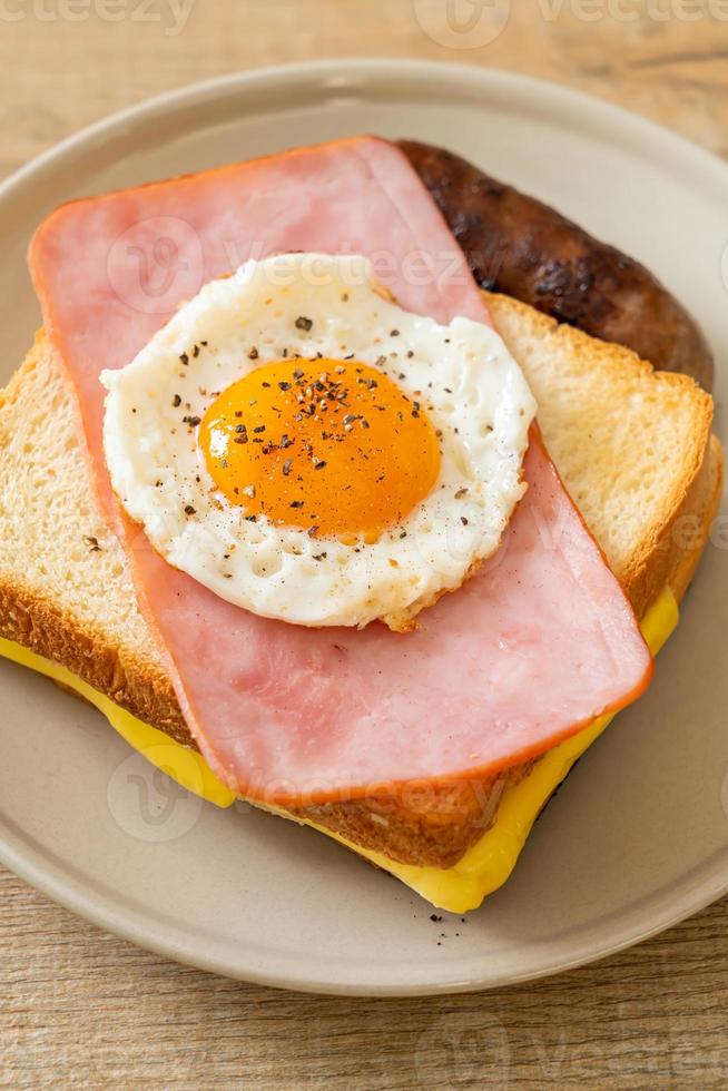 hausgemachtes Brot, gerösteter Käse, belegter Schinken und Spiegelei mit Schweinswurst zum Frühstück foto