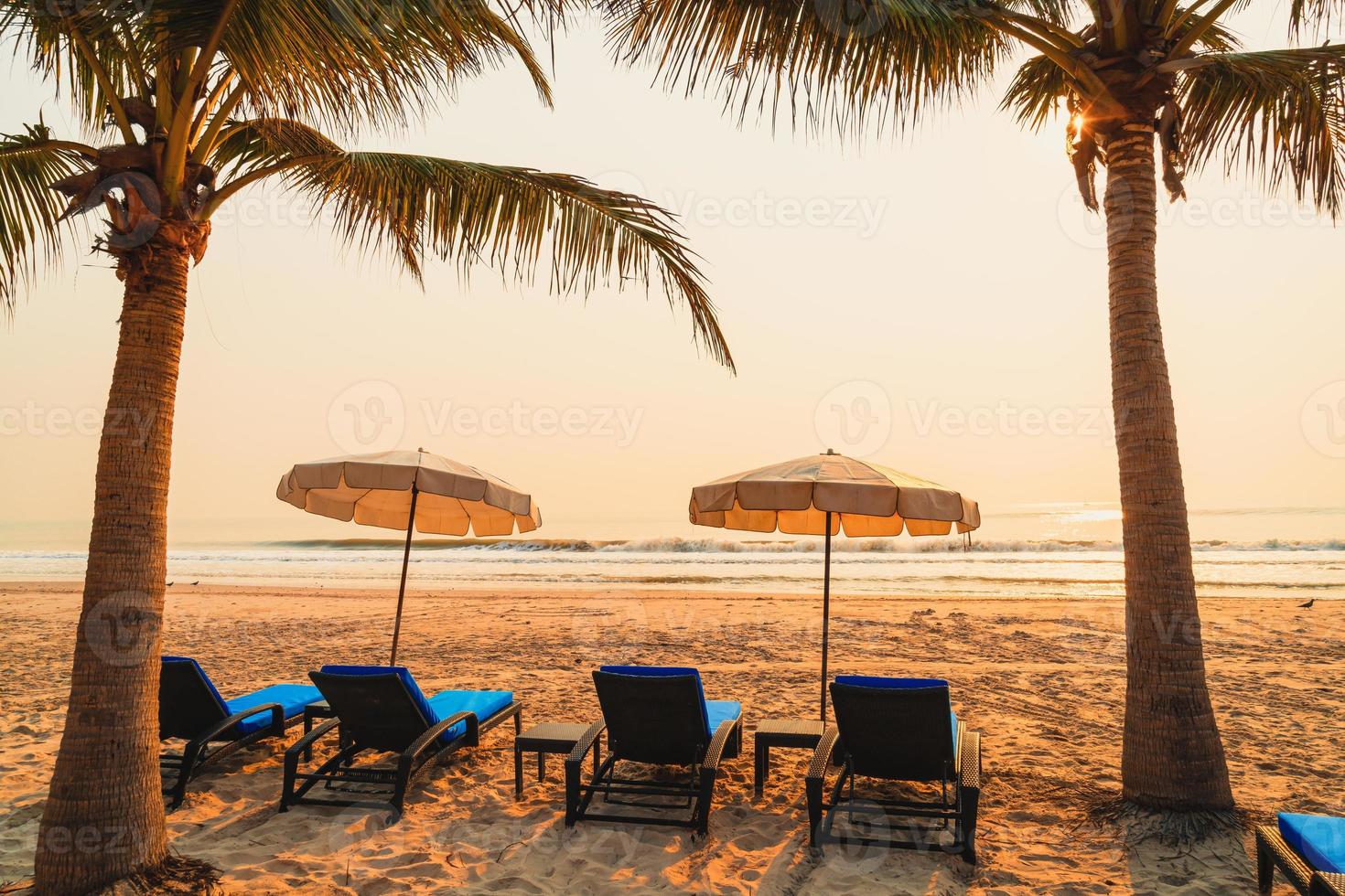 Sonnenschirm Strandkorb mit Palme und Meeresstrand bei Sonnenaufgang - Urlaubs- und Urlaubskonzept foto