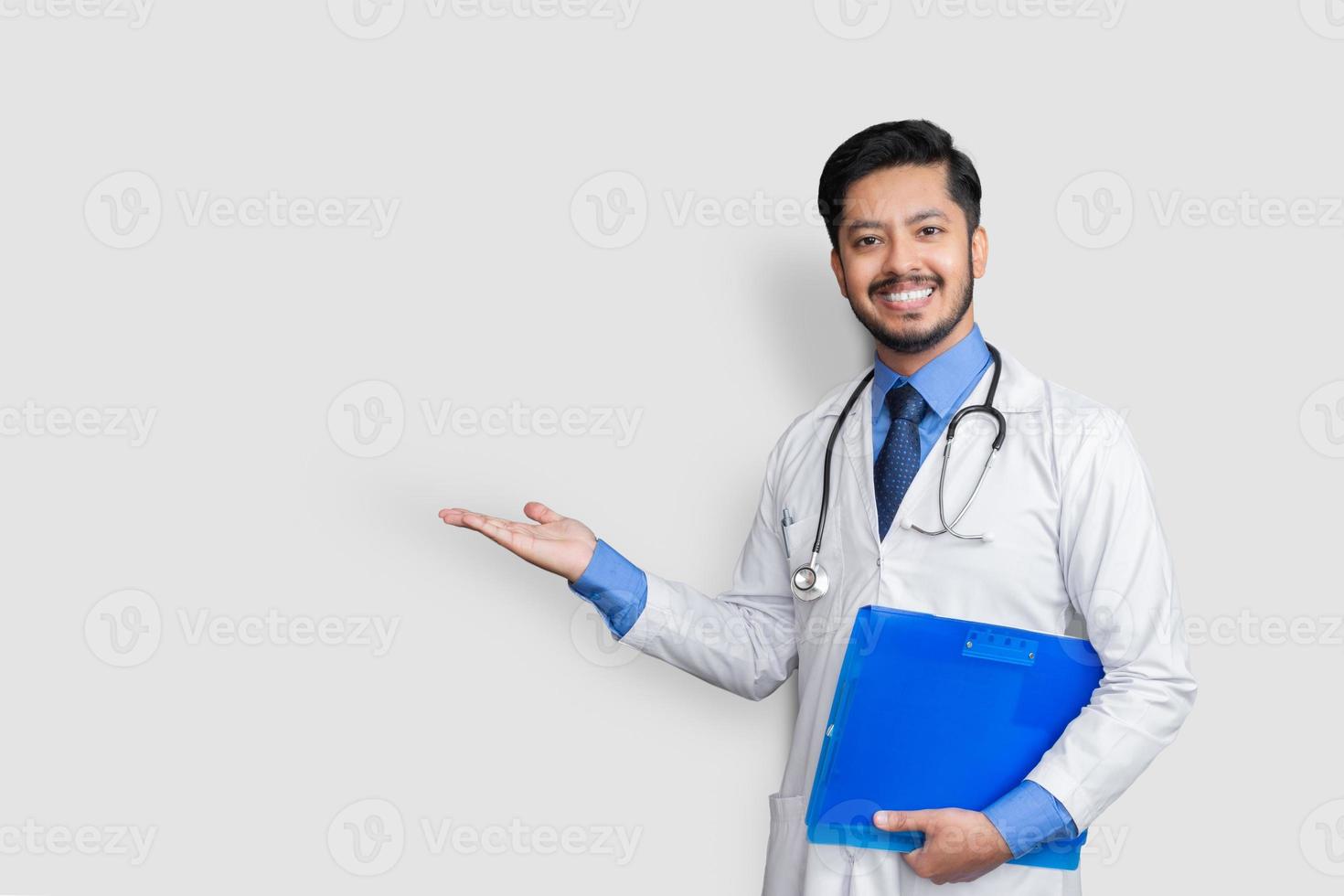 Arzt in Uniform lächelnd bei der Präsentation mit Patientenakte in der Hand isoliert auf weißem Hintergrund mit Kopienraum foto