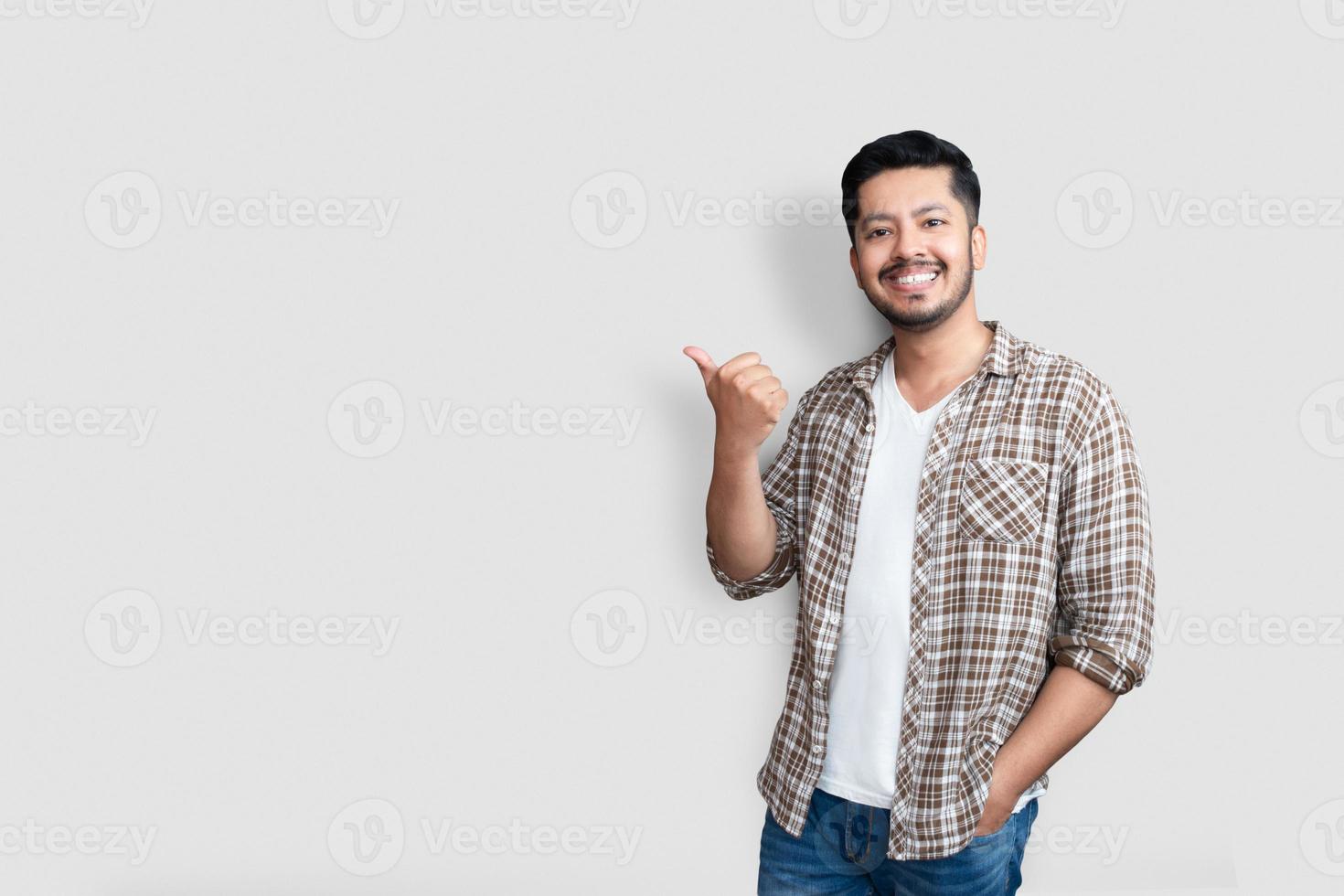 Erwachsener asiatischer Mann über isoliertem Hintergrund, der mit glücklichem Gesicht lächelt und mit Daumen nach oben auf die Seite zeigt. foto