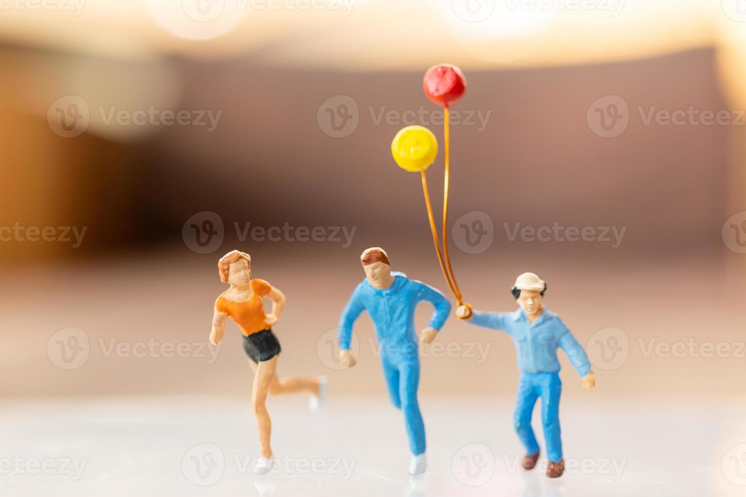 Miniaturmenschen, glückliche Familie, die mit Ballon läuft und spielt foto