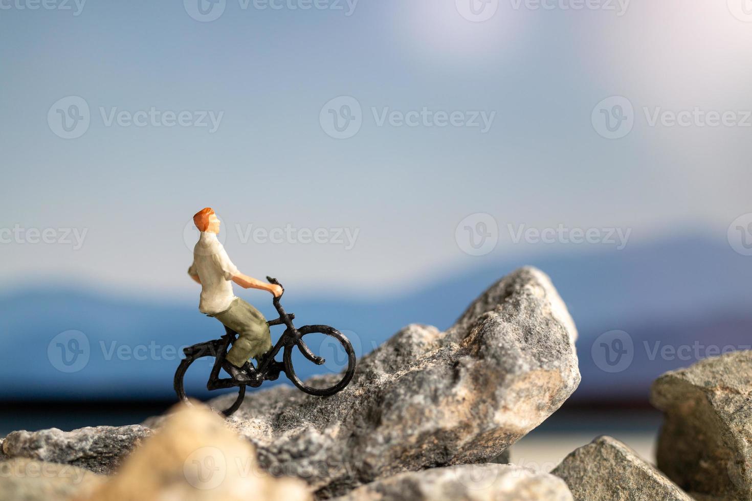 Miniaturmenschenreisender mit Fahrradfahren auf dem Felsen foto