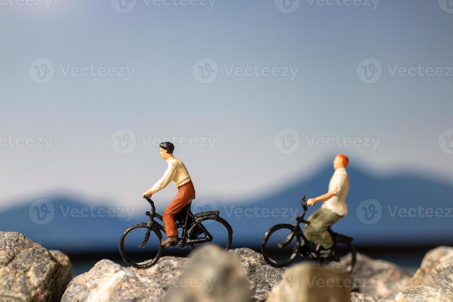 Miniaturmenschenreisender mit Fahrradfahren auf dem Felsen foto