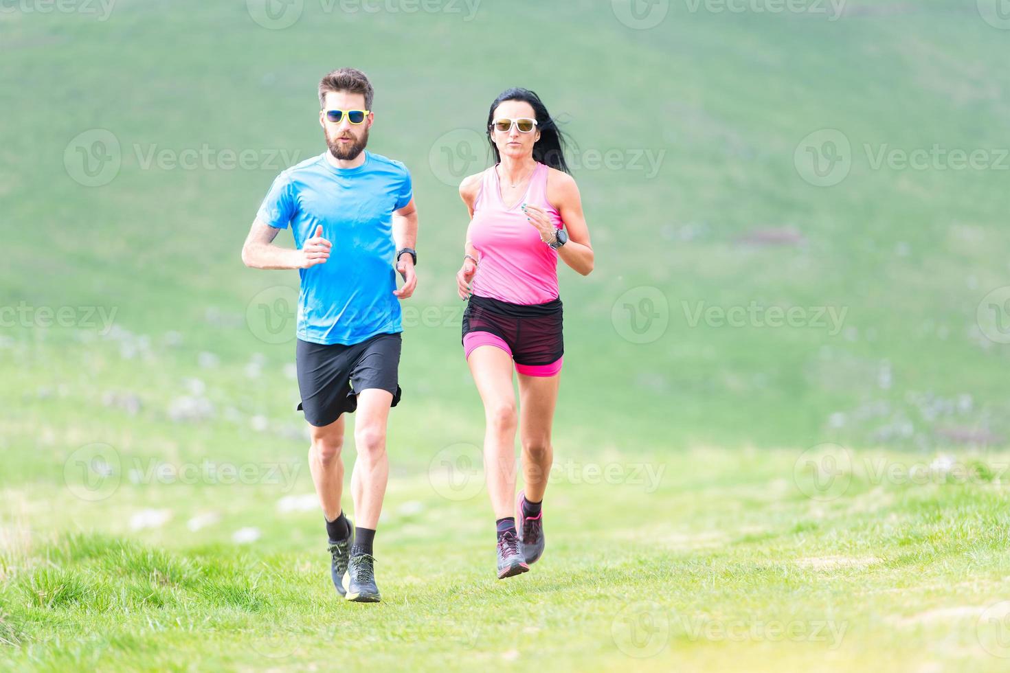 Aktion von Läufern auf hügeligen Wiesen im Sommer. Mann und Frau foto