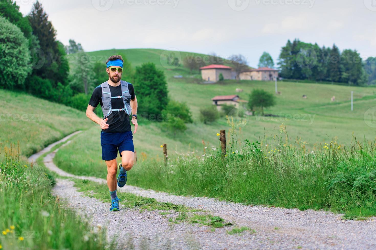 junger Sportler mit Bart läuft in ländlicher Hügellandschaft foto