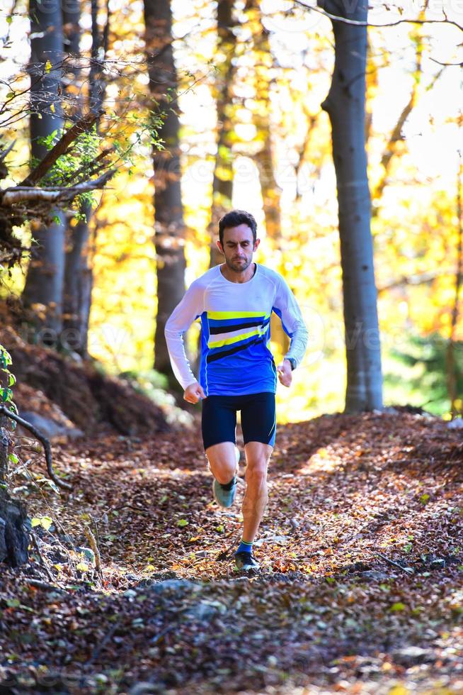 professioneller Laufsportler trainiert zwischen den Blättern des Waldes foto