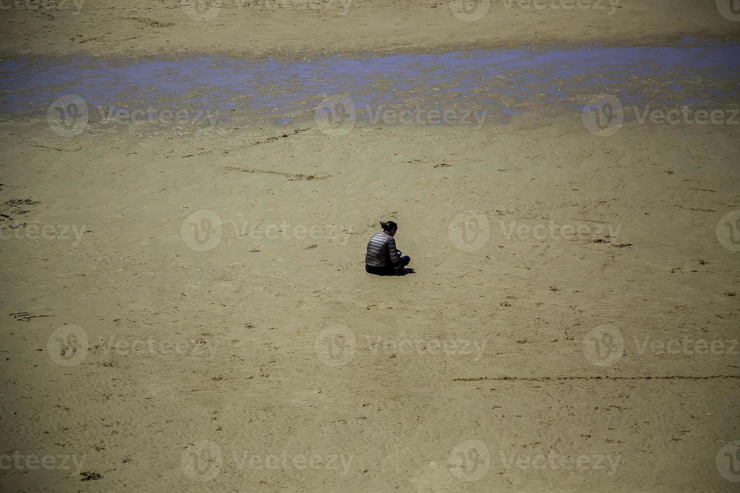 Frau sitzt am Strand foto