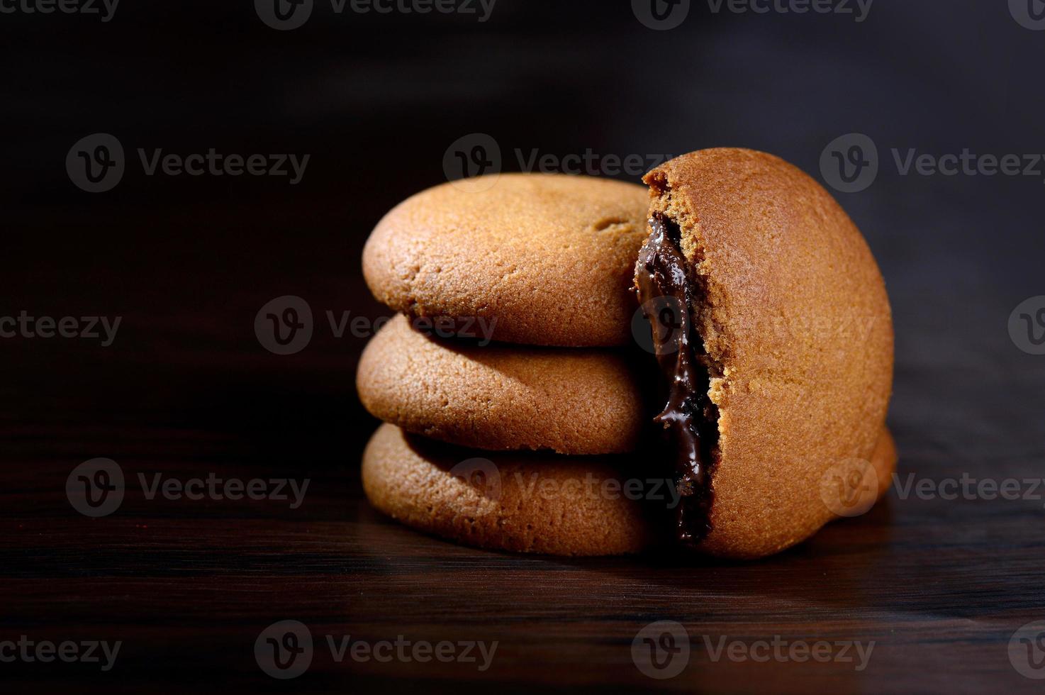 Kekse gefüllt mit Schokoladencreme. Schokoladencreme-Kekse. braune Schokoladenkekse mit Sahnefüllung auf schwarzem Hintergrund. foto