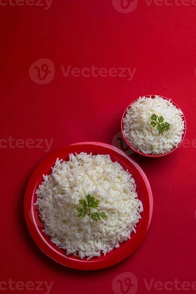 gekochter einfacher weißer Basmatireis in Schüssel und Teller auf rotem Grund. foto